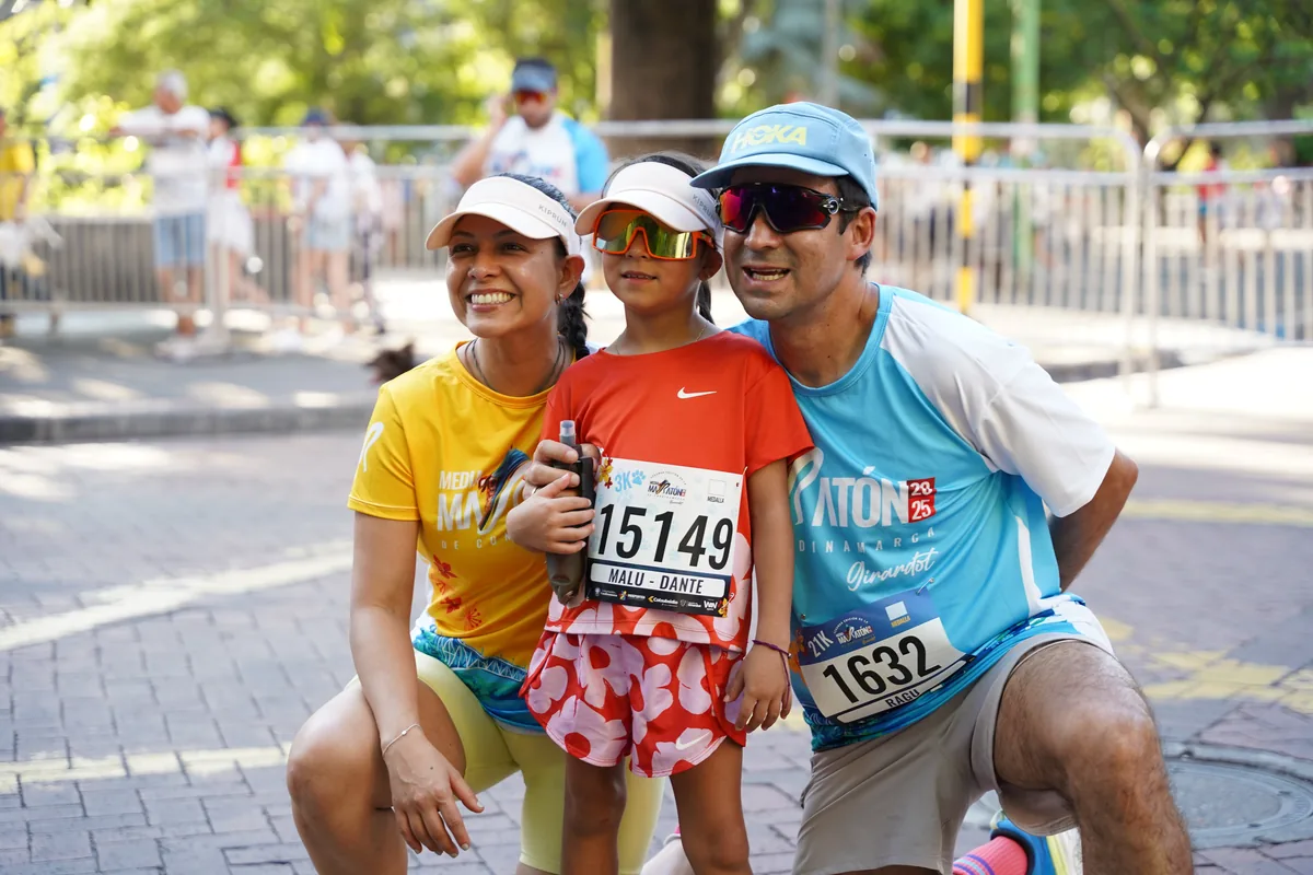 Una niña con su medalla de finalista, acompañada por dos adultos